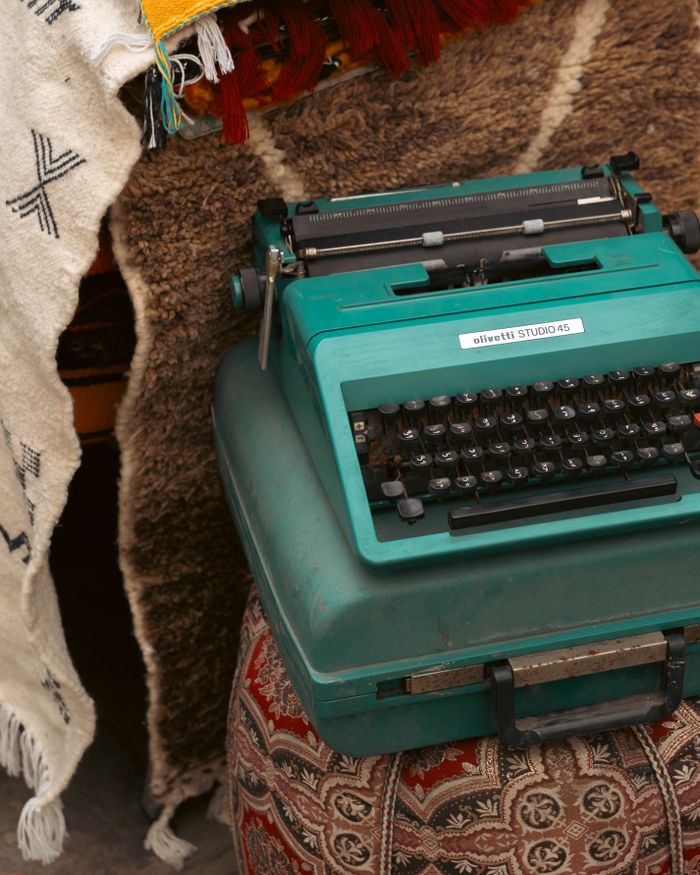 Classic Olivetti Studio 45 typewriter on a patterned ottoman, conveying retro vibes.